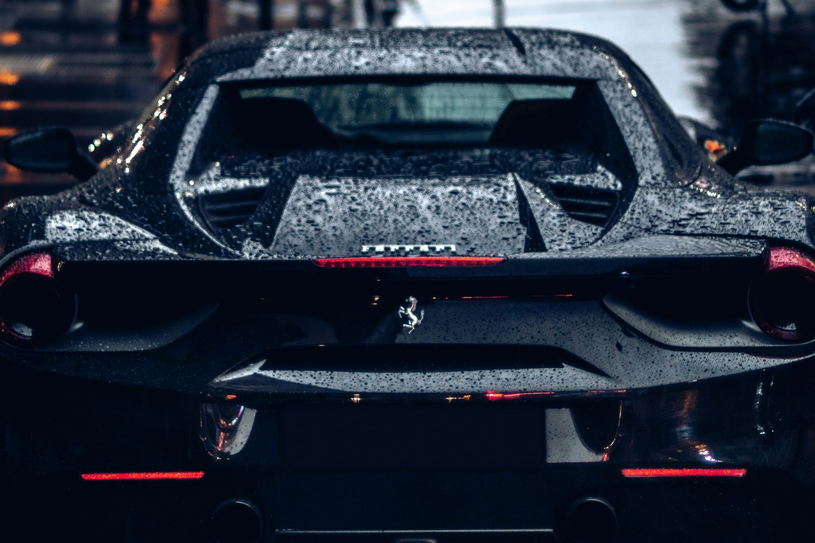A Ferrari on a rain-wet city street at dusk
